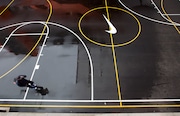 An employee speaks on a mobile phone as he strolls past a Swoosh on a basketball court at the Nike headquarters near Beaverton on March 22, 2018.