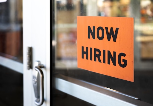 “now hiring” sign posted on business door