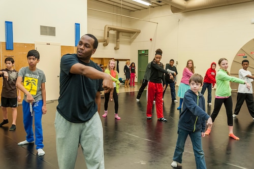 A man demonstrates dance moves to a classroom of students.