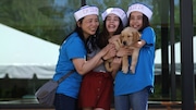 A family holds a yellow lab puppy that will be trained as a guide dog, during Fun Day at Guide Dogs for the Blind's Boring campus.