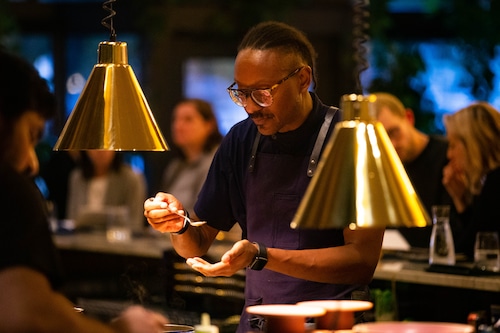 Chef in blue tastes food on spoon